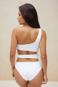 Woman wearing a white bikini set against a beige background
