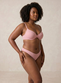 Woman wearing a pink bikini against a beige background