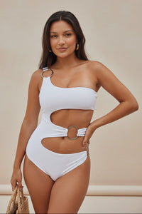 Woman wearing a white cut-out swimsuit against a beige background